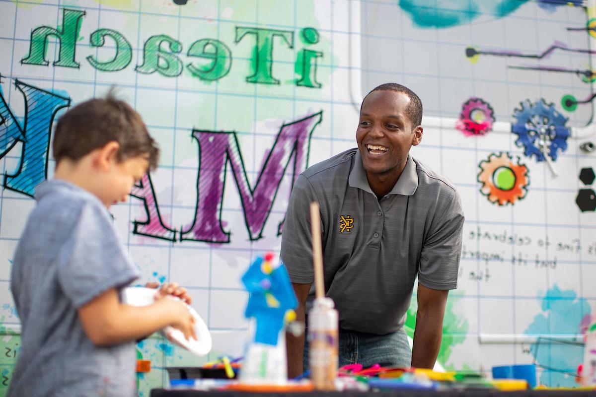 Man smiling at young child that is working on a project