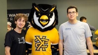 Two male students standing on either side of 正规博彩十大网站排名 mascot, Scrappy the Owl